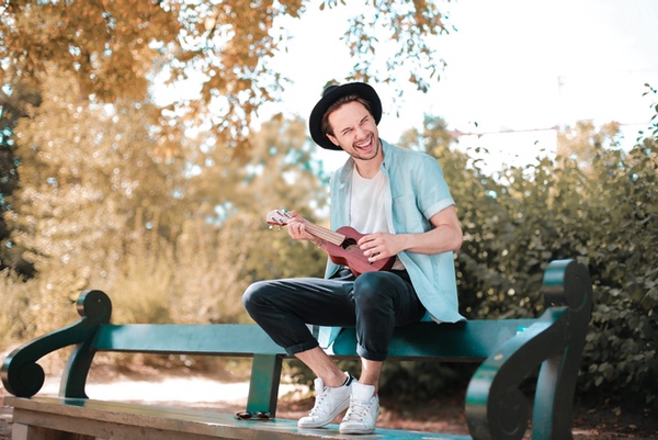 man-sitting-on-wooden-bench-using-ukulele-3761517-scaled
