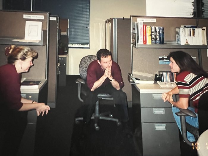 IT Adrienne Adrienne on the right, probably planning bank websites. Fat HTML and Javascript books on the shelf. Cubicle city, 1997.